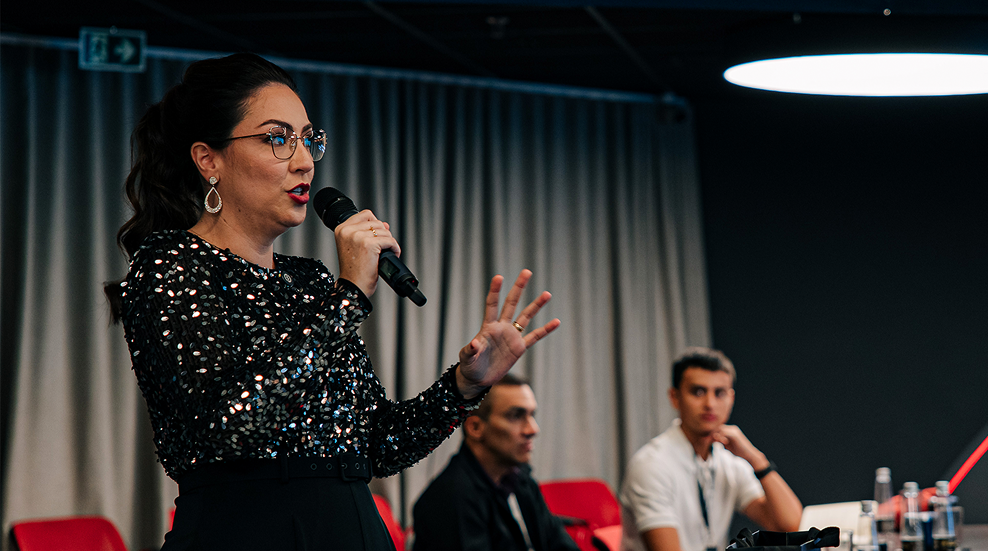 Camila falando ao microfone em painel